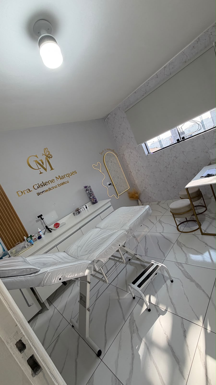 Consultório da Dra Gislene — maca de procedimento e logo dourado
